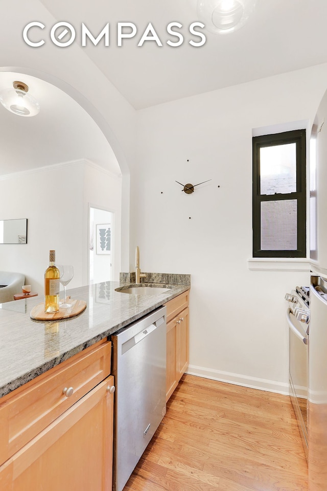 kitchen with light stone countertops, stainless steel appliances, light wood-style floors, light brown cabinets, and a sink