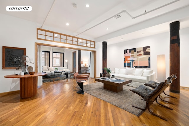 living area featuring light wood-style flooring, visible vents, and baseboards