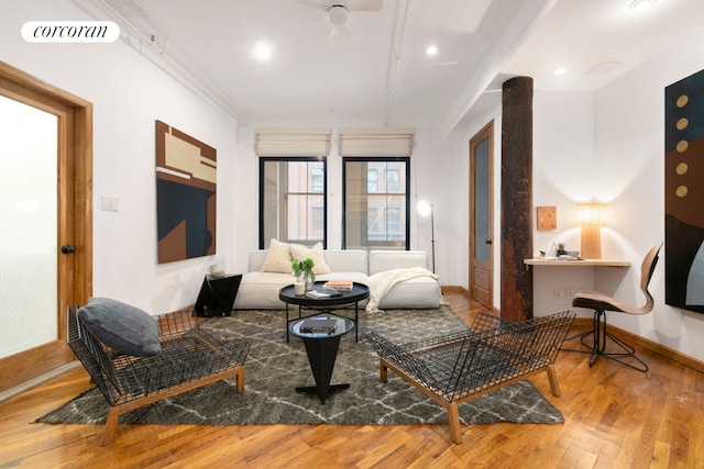 living room featuring ornamental molding, wood-type flooring, visible vents, and baseboards