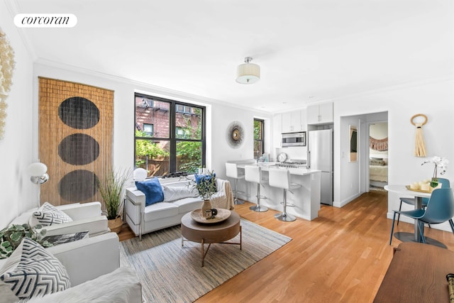 living room with baseboards, visible vents, crown molding, and light wood finished floors