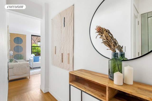 hall featuring light wood-style floors, visible vents, and baseboards