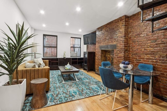 living room with brick wall, recessed lighting, wood finished floors, and a fireplace