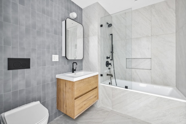 full bath featuring toilet, tiled shower / bath, tile walls, and vanity