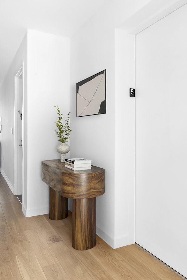 corridor featuring light wood-type flooring and baseboards