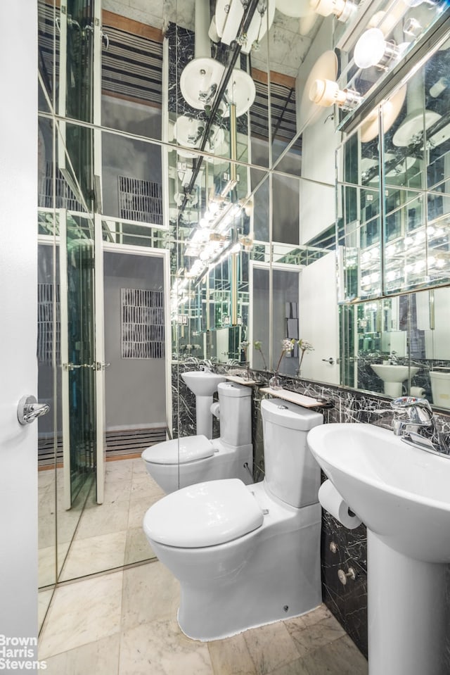 bathroom with a bidet, toilet, and tile patterned floors