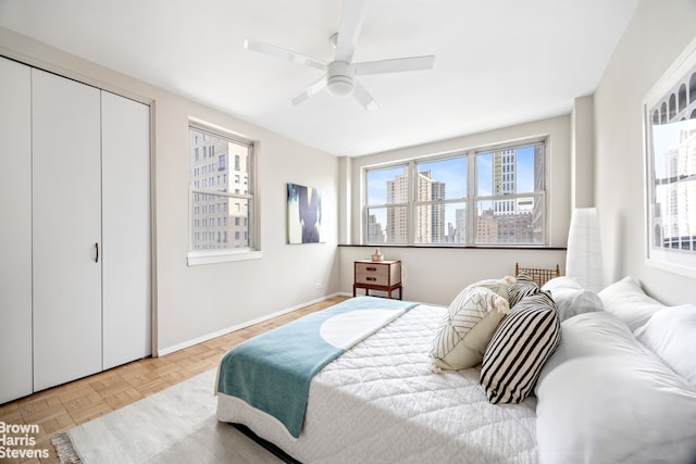 bedroom with ceiling fan, multiple windows, baseboards, and a closet