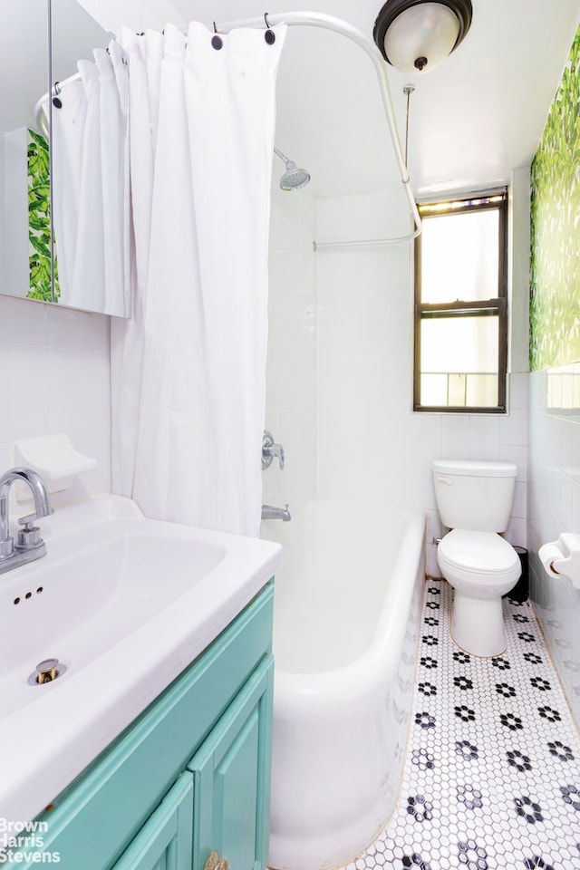 full bath with shower / bath combo, toilet, tile patterned flooring, vanity, and tile walls