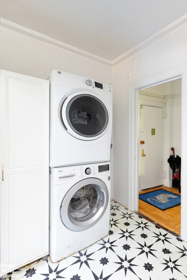 laundry room with stacked washer and clothes dryer, light floors, and laundry area