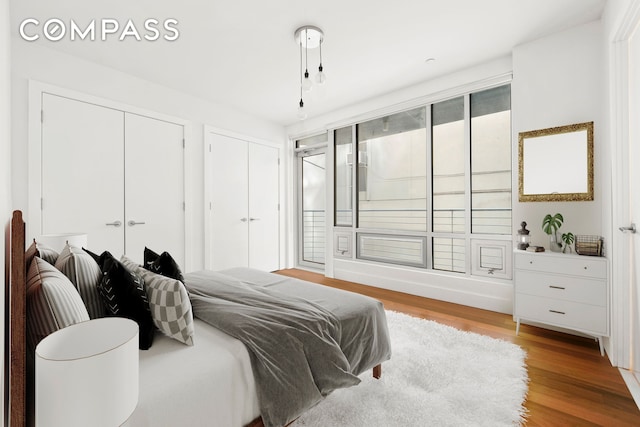 bedroom with two closets and wood finished floors