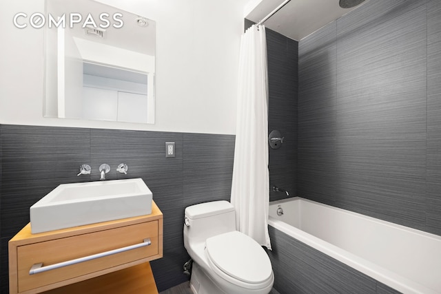 full bath featuring shower / tub combo, tile walls, vanity, and toilet