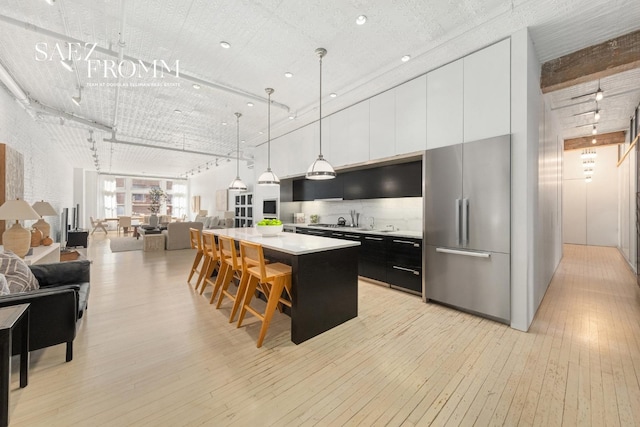 kitchen with light wood-style flooring, open floor plan, a center island, high quality fridge, and light countertops