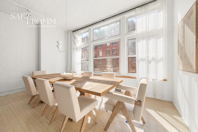 dining area with light wood finished floors and brick wall