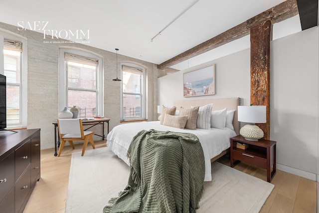 bedroom featuring beam ceiling and light wood-style floors