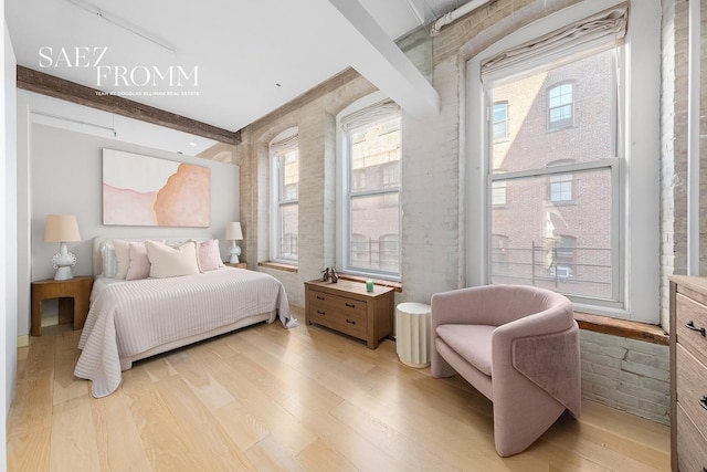 bedroom with multiple windows, light wood-type flooring, and beam ceiling