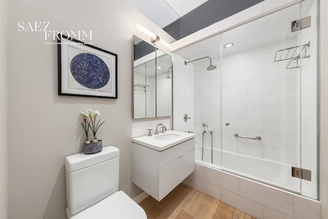 full bath featuring vanity, tiled shower / bath combo, wood finished floors, and toilet