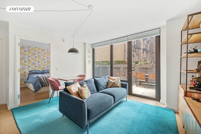 living area with visible vents, light wood-style flooring, and expansive windows