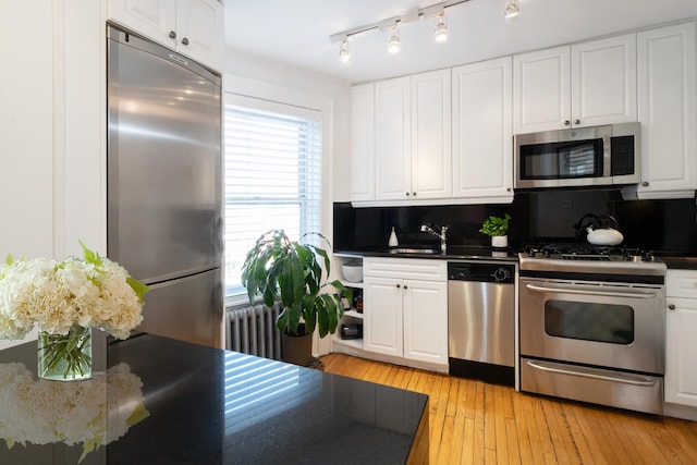 kitchen with white cabinetry, dark countertops, light wood-type flooring, and appliances with stainless steel finishes