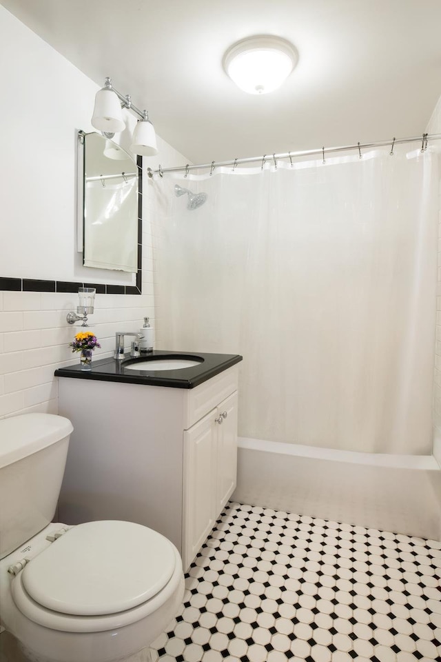 full bath featuring tile walls, toilet, vanity, and shower / bath combo