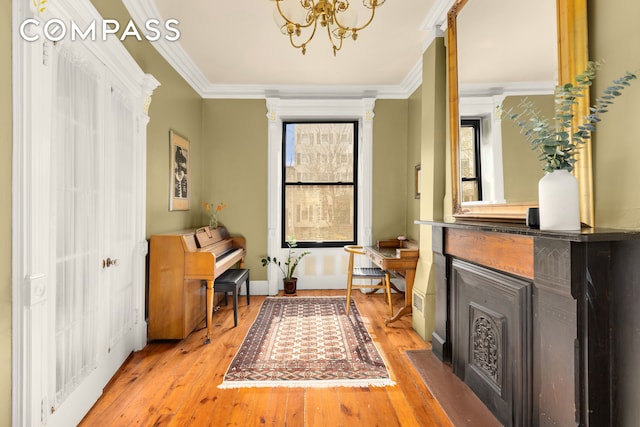 living area with hardwood / wood-style floors, crown molding, and a chandelier