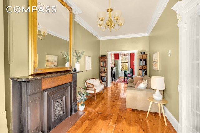 interior space featuring baseboards, a chandelier, a fireplace with flush hearth, ornamental molding, and light wood-style flooring