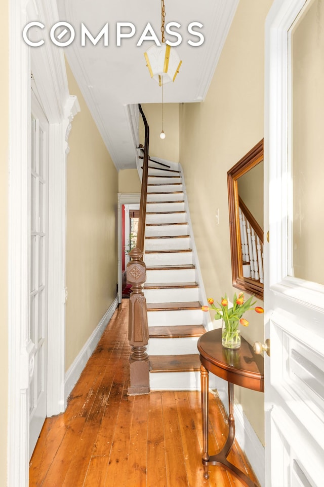 staircase with baseboards, hardwood / wood-style floors, and crown molding