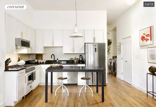 kitchen featuring dark countertops, visible vents, appliances with stainless steel finishes, independent washer and dryer, and a kitchen breakfast bar