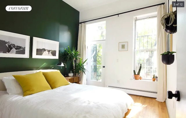 bedroom with a baseboard heating unit and wood finished floors