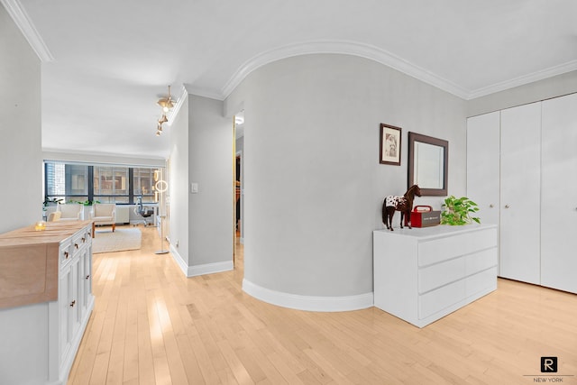 hallway with baseboards, ornamental molding, and light wood finished floors