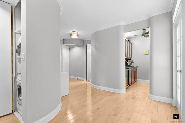 washroom featuring ceiling fan, stacked washer and dryer, laundry area, light wood finished floors, and crown molding