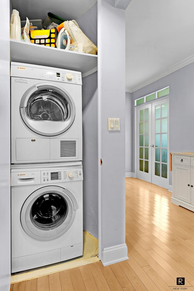 clothes washing area featuring laundry area, ornamental molding, baseboards, french doors, and stacked washer / drying machine