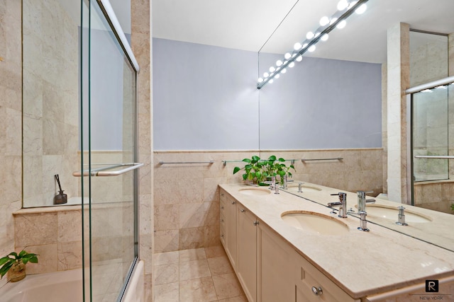 full bath with a sink, tile walls, and double vanity