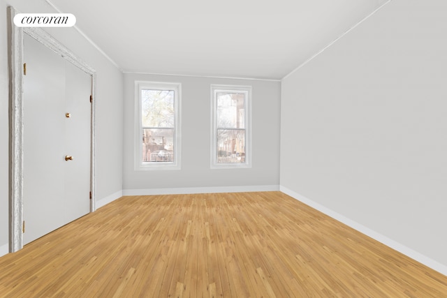 spare room with visible vents, baseboards, crown molding, and light wood finished floors