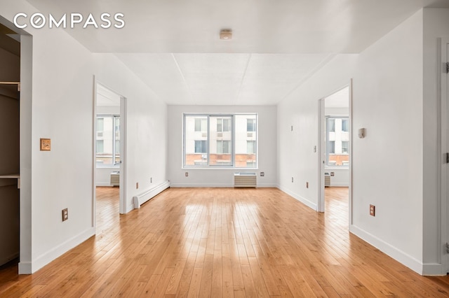 unfurnished bedroom featuring light wood finished floors, baseboards, and a baseboard heating unit