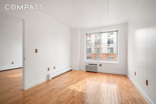 unfurnished room with baseboard heating, a wall unit AC, light wood finished floors, and baseboards