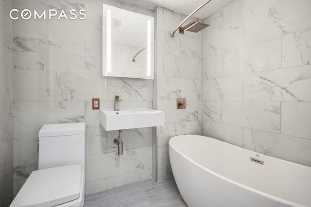 bathroom featuring tile walls, a freestanding bath, and toilet