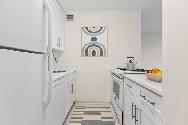 kitchen featuring white appliances, white cabinetry, visible vents, and a sink