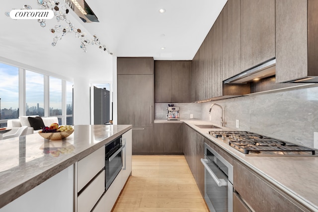 kitchen with stainless steel appliances, light wood-style flooring, modern cabinets, and a sink