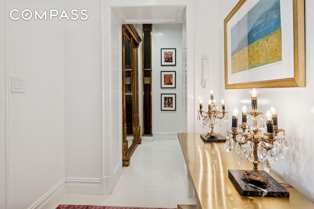 hall featuring baseboards and a notable chandelier