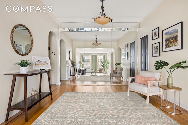 hallway with baseboards, arched walkways, and wood finished floors