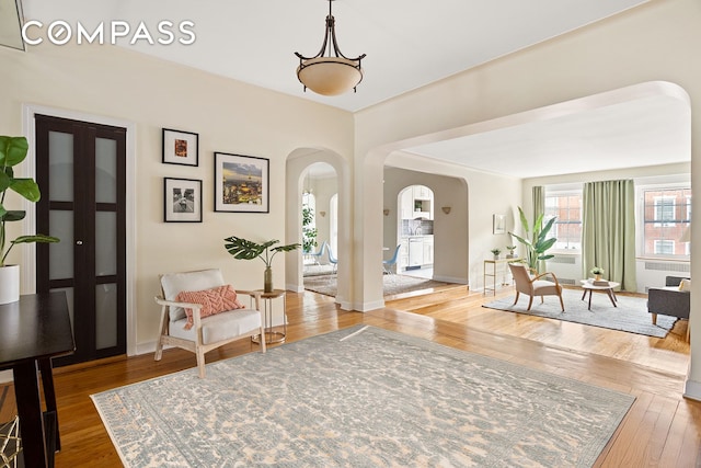 entrance foyer with arched walkways, wood-type flooring, and baseboards