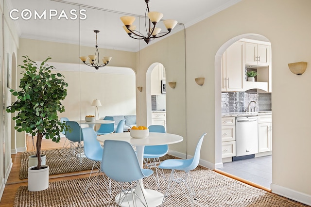 dining space with an inviting chandelier, baseboards, ornamental molding, and light wood finished floors