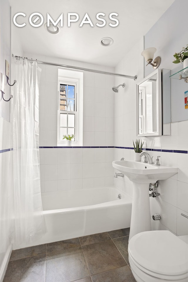 bathroom featuring toilet, shower / bath combo, and tile walls