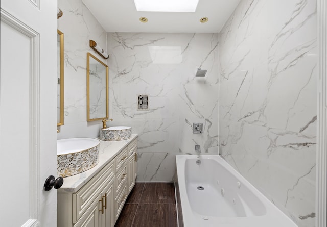 bathroom with a sink, a skylight, double vanity, and a combined bath / shower with jetted tub