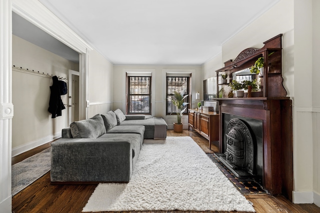 living area featuring crown molding, a fireplace, dark wood-style flooring, and baseboards