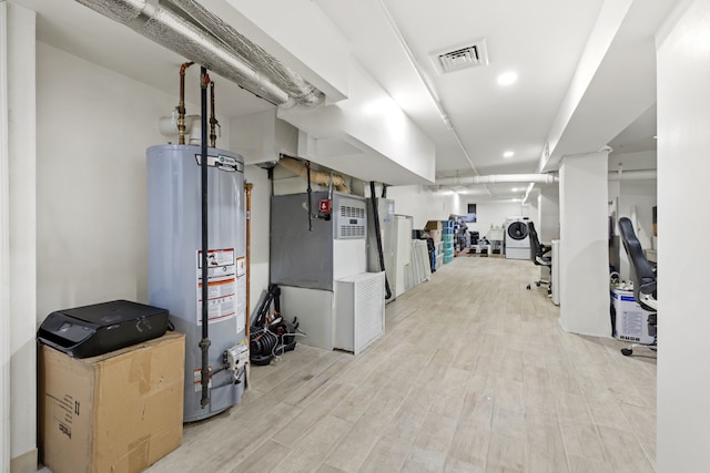 finished basement with light wood finished floors, visible vents, and gas water heater