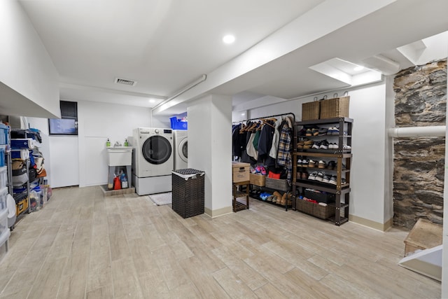 finished below grade area with wood finished floors, visible vents, and washing machine and clothes dryer