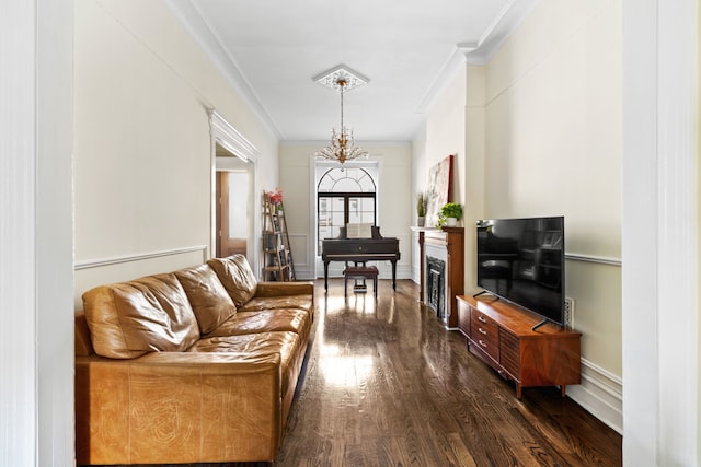 living area with a notable chandelier, a fireplace, dark wood-style flooring, and ornamental molding