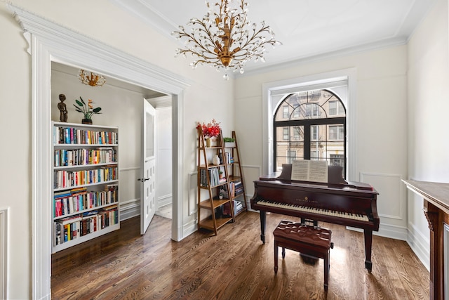 sitting room with an inviting chandelier, wood finished floors, and ornamental molding