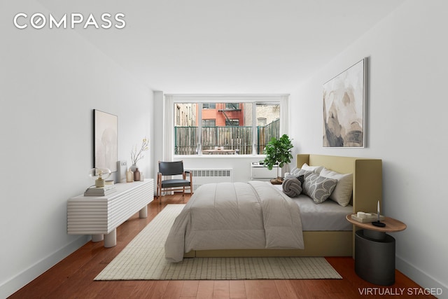 bedroom with radiator heating unit, baseboards, and wood finished floors