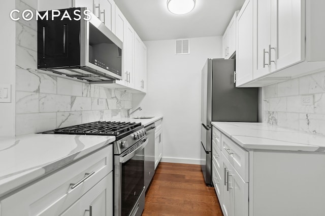 333 E 14th St Unit 2C, New York City, NY 10003 - kitchen with appliances with stainless steel finishes, white cabinets, dark wood-style flooring, and decorative backsplash